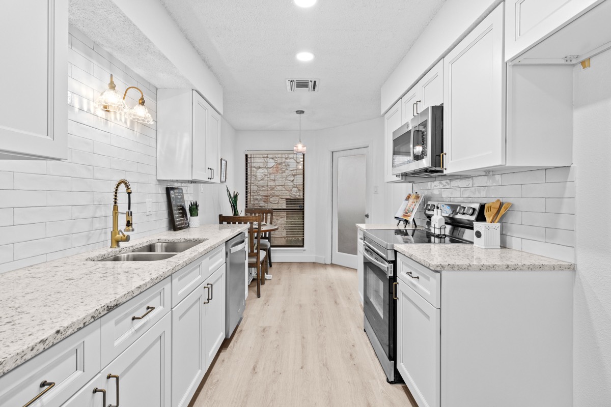 Bright renovated galley kitchen with white cabinets and granite counters